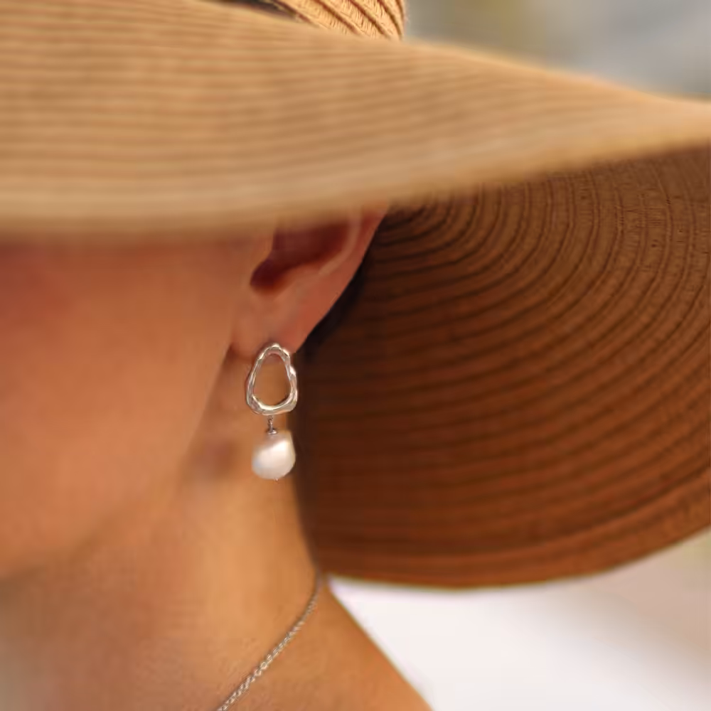 Model in beach hat wear gold pearl drop earrings
