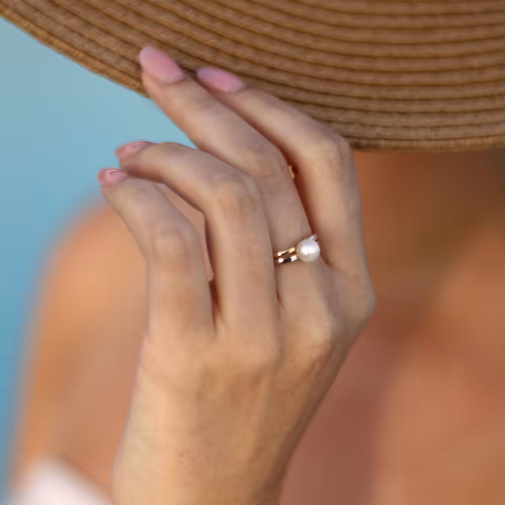 Close up of hand holding straw hat with pearl ring