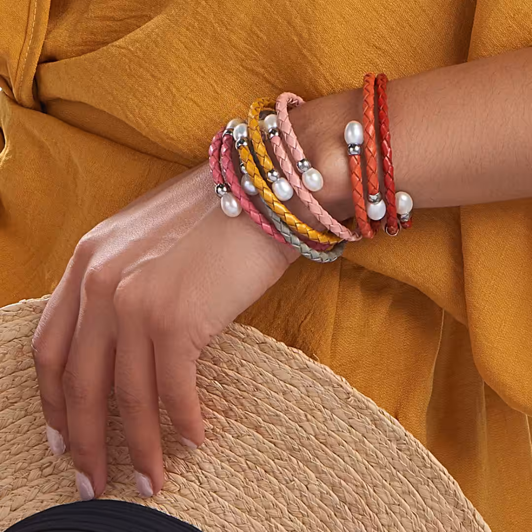 Close up of arm wearing five stacked, colourful pearl bracelets