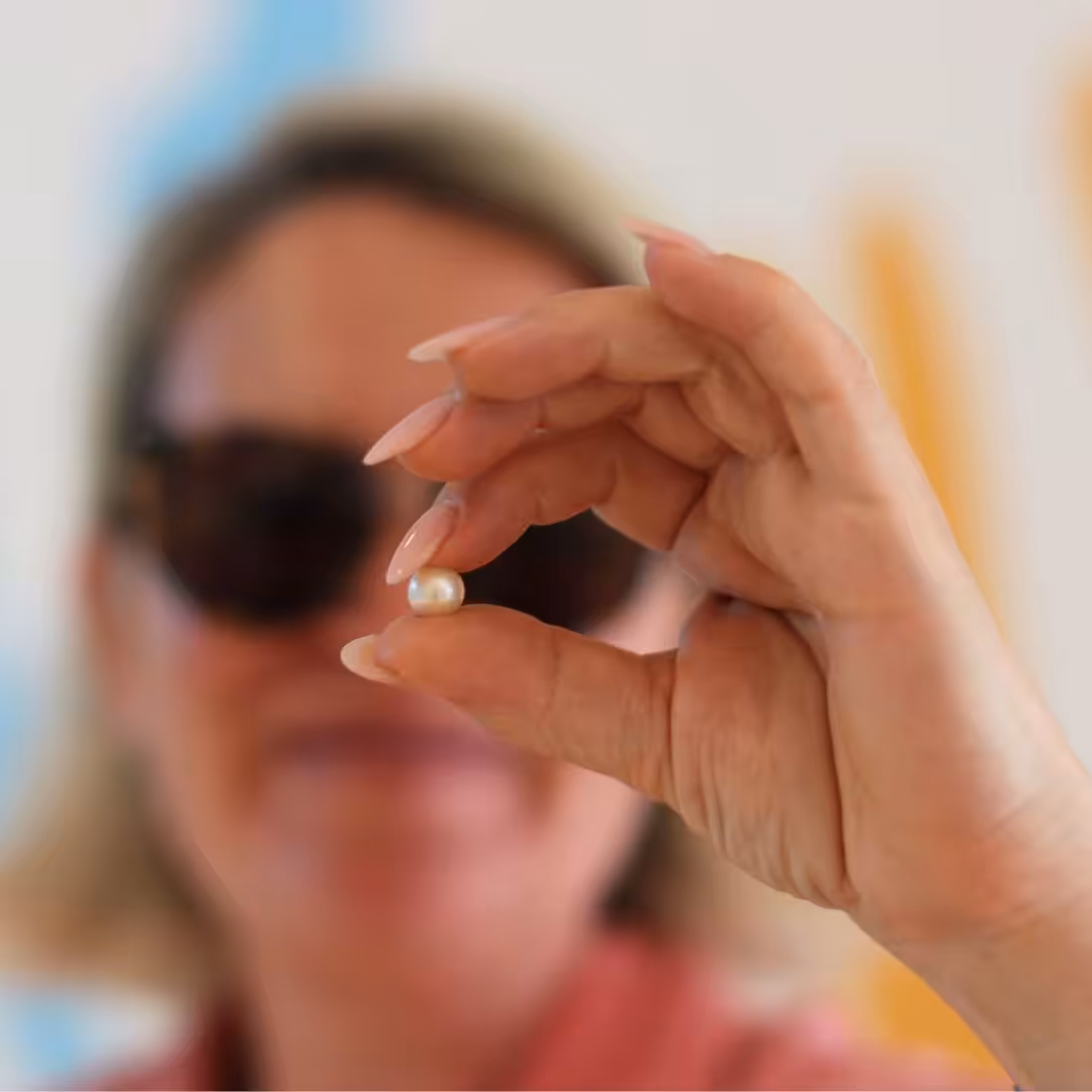 lady holding up a pearl from their pick a pearl experience