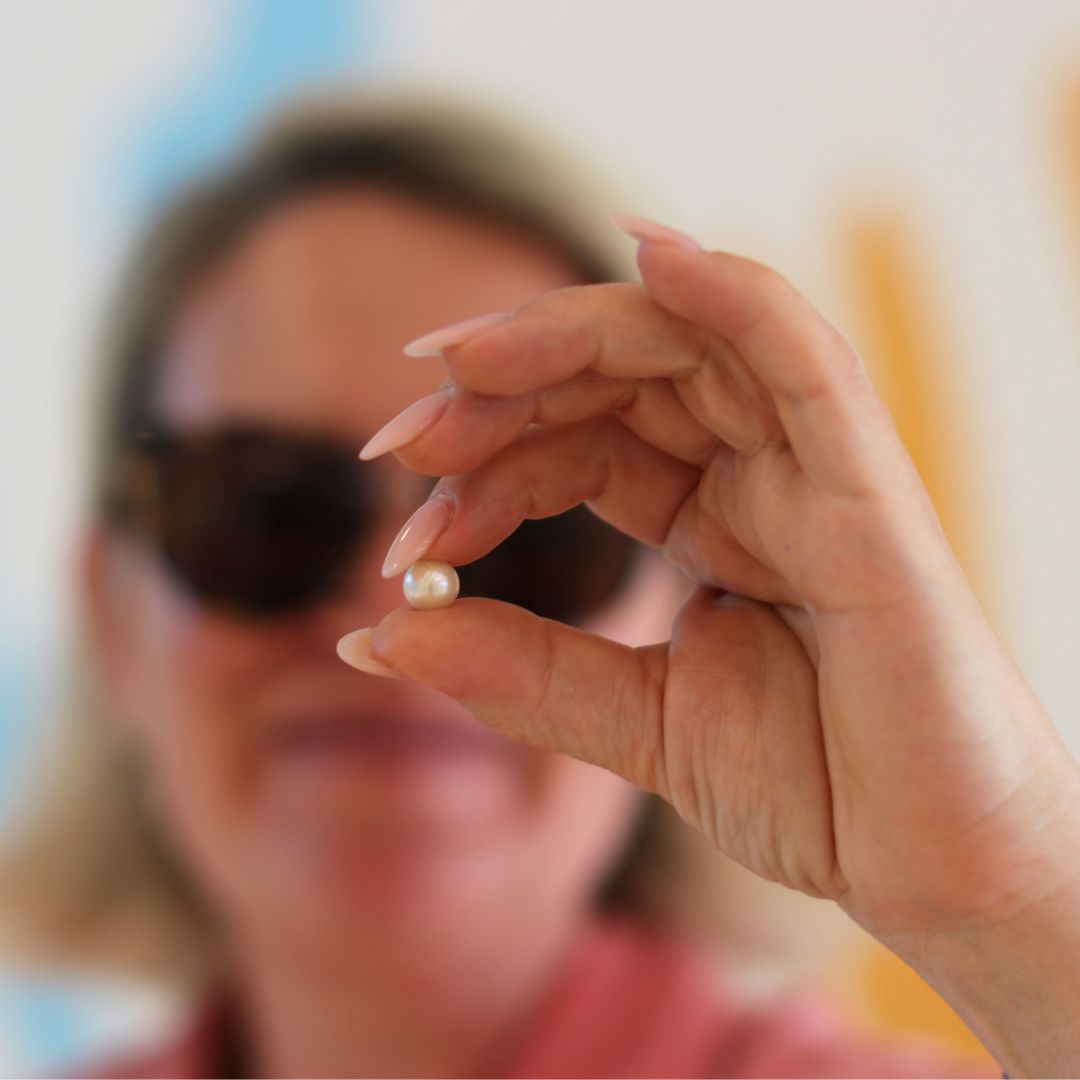 lady holding up a pearl from their pick a pearl experience